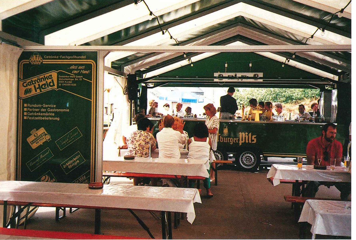 Ausschankwagen von Getränke Heid im Festzelt, Gäste an Biertischgarnituren